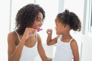 mother and daughter brushing their teeth together
